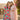 Two women in colorful traditional outfits standing outdoors with a blurred background