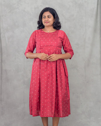 Woman wearing a red dress with white patterns against a gray background