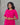 Woman wearing a bright pink maternity dress with white patterns against a gray background