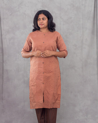 Woman wearing a brown kurta against a gray background