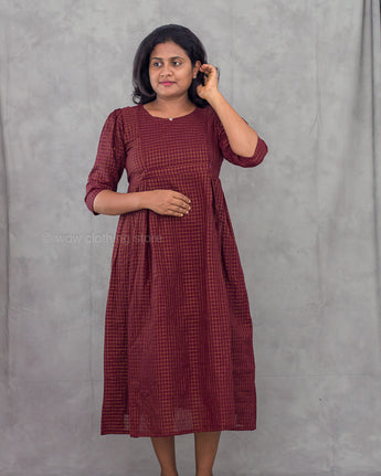 Woman wearing a maroon checkered dress against a gray background