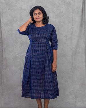 Woman wearing a blue checkered dress against a gray background