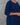 Person wearing a blue kurta with colorful buttons and kalamkari pants on a gray background