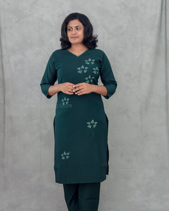 Woman wearing a green dress with floral patterns against a gray background