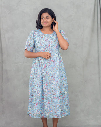 Woman wearing a light blue floral feeding kurti against a gray background