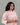 A women wearing a floral printed lace work pink color top with plain beige bottom on a grey background
