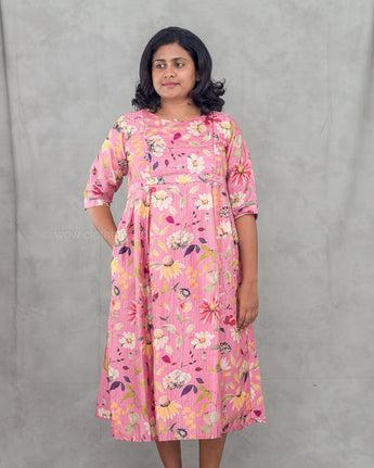 Woman wearing a pink floral feeding top against a gray background
