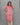 Woman wearing a pink floral kurti with beige pants against a gray background