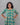 Woman wearing a teal floral dress against a gray background
