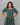 Woman wearing a green patterned dress against a gray background