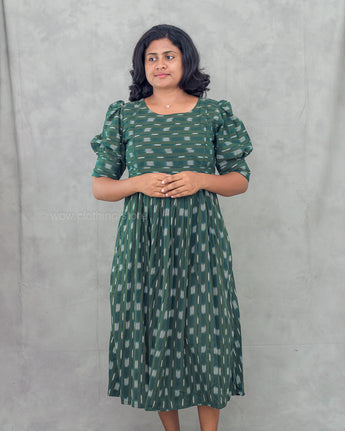 Woman wearing a green ikkat maternity kurti against a gray background