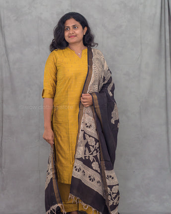 Woman wearing a yellow kurti with a kalamkari dupatta against a gray background
