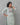 A lady wearing a plain top with elegant neck work linen kurti on a grey background