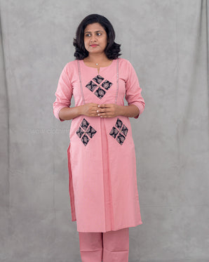 Woman wearing a pink traditional outfit with black patterns on a gray background