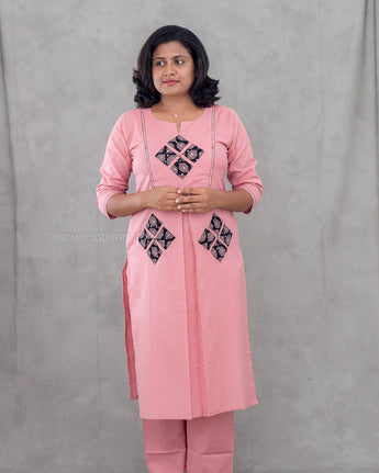 Woman wearing a pink traditional outfit with black patterns on a gray background