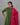 Woman wearing a green kurta with red patterns and a red dupatta against a gray background