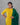 Woman wearing a yellow kurta with green dupatta against a gray background
