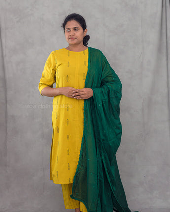 Woman wearing a yellow kurta with a green dupatta against a gray background
