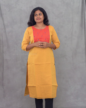 Woman wearing a yellow kurti with black pant against a gray background