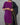 Person wearing a purple kurta with a black saree draped over the shoulder against a gray background.