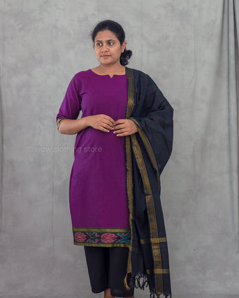 Woman wearing a purple kurta with a black dupatta draped over her shoulder against a gray background