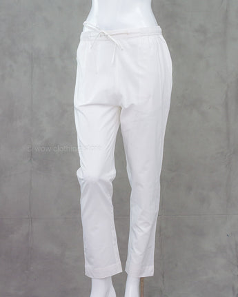 White cotton pants on a mannequin against a gray background