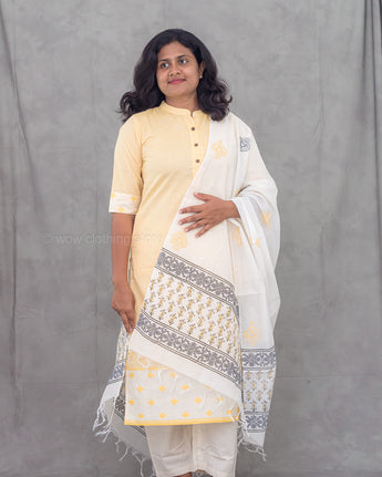 Woman wearing a yellow kurti with a white and gray printed dupatta against a gray background