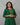 Woman wearing a green traditional outfit with colorful patterns on a gray background