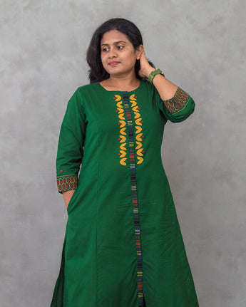 Woman wearing a green dress with colorful patterns on a gray background