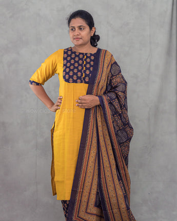 Woman wearing a yellow kurta with a patterned dupatta against a gray background