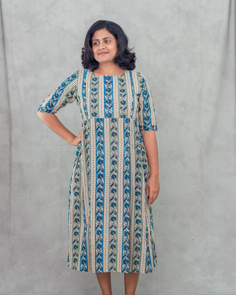 Woman wearing a blue patterned feeding dress against a gray background