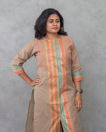 Woman wearing a beige kurta with colorful stripes against a gray background