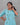 Woman wearing a light blue floral dress against a gray background