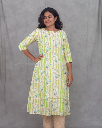 Woman wearing a green and white floral patterned kurti against a gray background