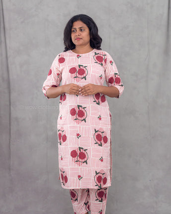 Woman wearing a pink floral kurta with pants against a gray background