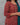 Woman wearing a red floral patterned dress with a teal dupatta against a gray background