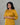 Woman wearing a mustard yellow kurta set with floral embroidery against a gray background
