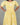 Yellow dress with white floral pattern worn by a person on a gray background