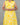 A women wearing yellow color cotton a-line kurti with back rope on a grey background
