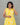 A women wearing yellow color cotton a-line kurti with back rope on a grey background