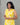 A women wearing yellow color collored cotton a-line kurti with back rope on a grey background