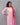 Woman wearing a pink and white kurti with a matching dupatta against a gray background