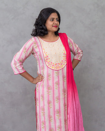Woman wearing a pink and white kurti with a matching dupatta against a gray background