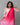 Woman wearing a pink and white traditional outfit with a pink dupatta against a gray background