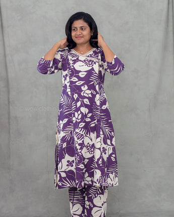Woman wearing a purple and white patterned dress against a gray background
