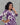 Woman wearing a purple and white patterned dress against a gray background