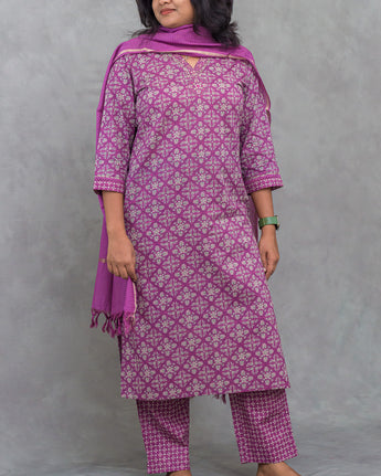 Woman wearing a purple floral patterned outfit against a gray background