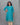 Woman wearing a blue floral kurti with beige pants against a gray background