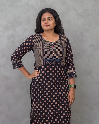 A lady wearing a printed black cotton kurti on a grey background