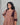 Woman wearing a brown striped maternity kurti with maroon accents against a gray background